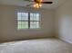 Bedroom with neutral carpet, a ceiling fan with light fixture, and a double window looking out on trees at 10949 Harness Way, Indianapolis, IN 46239