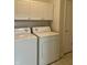 Clean laundry room with white washer, dryer, upper cabinets, and neutral tiled floor at 10949 Harness Way, Indianapolis, IN 46239