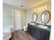 Bathroom featuring double sink vanity, new lighting, and stylish wood-look laminate flooring at 11147 Autumn Creek Ct, Indianapolis, IN 46229