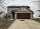 Front exterior of a brick and vinyl two-story home with a two-car garage and a well-manicured lawn at 11147 Autumn Creek Ct, Indianapolis, IN 46229