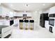 Bright, modern kitchen with white cabinets, marble-like flooring, an island with seating, and black appliances at 11149 Titania Ct, Noblesville, IN 46060