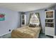 Bright bedroom with blue walls, white trim, and a comfy bed next to shelving units at 1123 Woodbridge Ln, Indianapolis, IN 46260