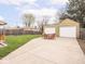 Spacious backyard featuring a two-car garage, well-kept lawn, and outdoor seating area with wood table at 1139 N Butler Ave, Indianapolis, IN 46219