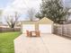Backyard featuring a two-car garage, well-kept lawn, and outdoor seating area with wood table at 1139 N Butler Ave, Indianapolis, IN 46219