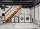 Basement laundry area features a wooden staircase, washer, dryer, and laundry sink at 1139 N Butler Ave, Indianapolis, IN 46219