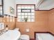 Retro bathroom featuring salmon tiles, a glass block window, and classic fixtures at 1139 N Butler Ave, Indianapolis, IN 46219
