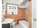 Bathroom features salmon tiles, glass block window, and a tub with shower curtain at 1139 N Butler Ave, Indianapolis, IN 46219