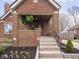 Close up of the charming brick home’s cozy covered porch with stairs leading up to the front door at 1139 N Butler Ave, Indianapolis, IN 46219