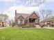 Charming brick home featuring a well-manicured lawn, landscaped garden beds, and a cozy covered front porch at 1139 N Butler Ave, Indianapolis, IN 46219