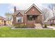Charming brick home featuring a well-manicured lawn, landscaped garden beds, and a cozy covered front porch at 1139 N Butler Ave, Indianapolis, IN 46219