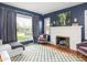 Comfortable living room with a fireplace, checkered rug, and large windows overlooking the exterior at 1139 N Butler Ave, Indianapolis, IN 46219