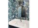 Elegant powder room featuring patterned wallpaper, gold mirror, modern lighting, and a sleek countertop at 11640 Ansley Ct, Zionsville, IN 46077