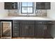 Stylish kitchenette features dark cabinets, stone backsplash, a beverage cooler, and modern fixtures at 11640 Ansley Ct, Zionsville, IN 46077