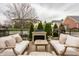 Outdoor living area with stylish seating around a fireplace and a lush green backdrop for luxurious entertaining at 12813 Chapel Square St, Carmel, IN 46032