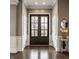 Elegant foyer with dark hardwood floors and a grand entrance featuring double doors and wainscoting at 12813 Chapel Square St, Carmel, IN 46032