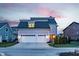 Well-lit two-car garage and driveway with a charming home exterior at twilight at 12813 Chapel Square St, Carmel, IN 46032