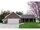 Charming brick home featuring an attached garage, well-manicured lawn, and covered front porch at 13116 N Departure W Blvd, Camby, IN 46113