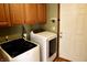 Efficient laundry room with wood cabinets, a white door to the backyard, and modern washer/dryer units at 13116 N Departure W Blvd, Camby, IN 46113