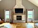 Cozy living room with a brick fireplace, TV, hardwood floors, and bright windows at 13116 N Departure W Blvd, Camby, IN 46113