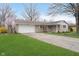 Front exterior view of a brick home with an attached garage and a blossoming tree in the yard at 1313 Roseway Dr, Indianapolis, IN 46219