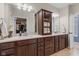 A bathroom featuring double sinks, dark wood cabinetry, a central storage cabinet, and neutral countertops at 13245 E 131St St, Fishers, IN 46037