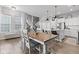 Open-concept dining area featuring a farmhouse table, wood floors, and views of the kitchen and staircase at 13245 E 131St St, Fishers, IN 46037