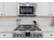 Modern stainless steel gas cooktop and microwave, paired with white subway tile and granite countertops at 13245 E 131St St, Fishers, IN 46037