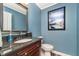 Updated powder room with framed mirror, dark wood vanity, and a blue accent wall with nature-inspired artwork at 14720 Warner Trl, Westfield, IN 46074
