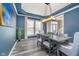 Stylish dining room with blue walls, hardwood floors, modern lighting, and seating for six around a gray wood table at 14720 Warner Trl, Westfield, IN 46074