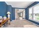 Comfortable living room with a hardwood table, blue accent wall, and bright lighting from a window and lamp at 14720 Warner Trl, Westfield, IN 46074