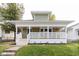 Charming home with a welcoming front porch, green siding, white trim, and well-manicured lawn at 1515 Dawson St, Indianapolis, IN 46203