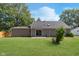 Lush backyard featuring a well-kept lawn with a gray home with sliding glass doors and mature trees at 1528 N Dukane Way, Indianapolis, IN 46214