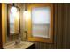 The bathroom features a golden framed mirror, quirky lighting, and a window bringing in natural light at 1700 S Perdieu Rd, Muncie, IN 47302