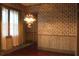 Dining room with hardwood floors, patterned wallpaper, vintage chandelier, and open doorway at 1700 S Perdieu Rd, Muncie, IN 47302
