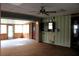 Room with linoleum ceiling, green paneled walls, ceiling fan, and entry to the sun room at 1700 S Perdieu Rd, Muncie, IN 47302