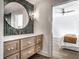 Bathroom featuring round mirror, green tiled backsplash, wood cabinet, and view to bedroom at 2428 S Morgantown Rd, Greenwood, IN 46143
