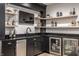 Home wet bar with beverage coolers, sink, dark cabinets, granite countertop, floating shelves, and TV at 2428 S Morgantown Rd, Greenwood, IN 46143