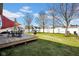 An open backyard featuring a wooden deck, with a trampoline and a white fence, and grassy lawn at 2468 Wyndham S Pl, Columbus, IN 47203