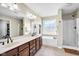Bathroom featuring a double sink, bathtub, walk-in shower, and large window at 2468 Wyndham S Pl, Columbus, IN 47203