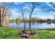 Scenic backyard view overlooking a serene pond, framed by trees, and features a fire pit ready for enjoying the outdoors at 3771 Lakewood Dr, Greenfield, IN 46140