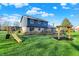 Large backyard with a play structure, wooden deck, and mature trees, perfect for Gathering activities at 3771 Lakewood Dr, Greenfield, IN 46140