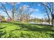 Scenic view of a sprawling backyard leading to a tranquil lake, surrounded by mature trees and lush greenery at 3771 Lakewood Dr, Greenfield, IN 46140