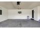 Spacious garage with white walls, concrete floor, TV, utility door, and overhead storage at 3771 Lakewood Dr, Greenfield, IN 46140