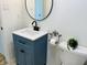 Bathroom with a modern blue vanity, white countertops, and a round decorative mirror at 414 Glendale Dr, Columbus, IN 47201