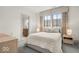 Bright bedroom with a large window, soft carpeting, and neutral decor; ensuite bathroom entrance at 583 Exmoor Dr, Carmel, IN 46032