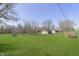Spacious yard with green grass, mature trees and an outbuilding in the background at 5913 W Maple Dr, Frankton, IN 46044
