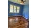 Cozy bedroom with hardwood floors, bright blue walls, ceiling fan and a multi-paned window at 6206 W Us Highway 40, Stilesville, IN 46180