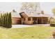Spacious backyard with a well-maintained lawn, mature trees, brick siding, and three-car garage at 6712 Forrest Commons Blvd, Indianapolis, IN 46227