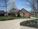 Charming brick home with a well-manicured lawn, flowering tree and inviting circular driveway at 6712 Forrest Commons Blvd, Indianapolis, IN 46227