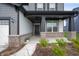 Covered front porch featuring brick base pillars, dark trim and front door, and manicured landscaping at 6925 Sable Point Dr, Brownsburg, IN 46112